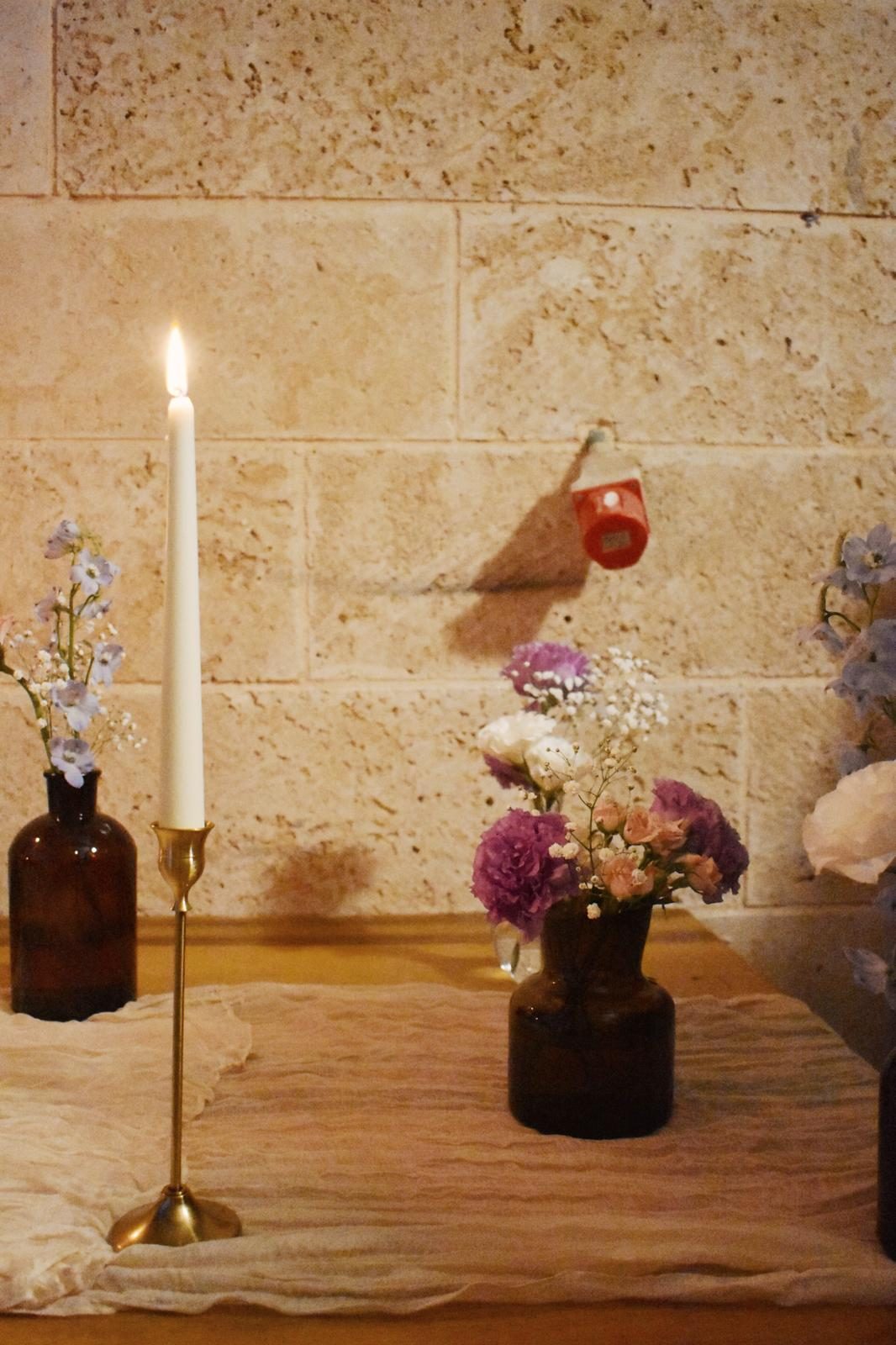 נר דולק ופרחים על רקע אבן